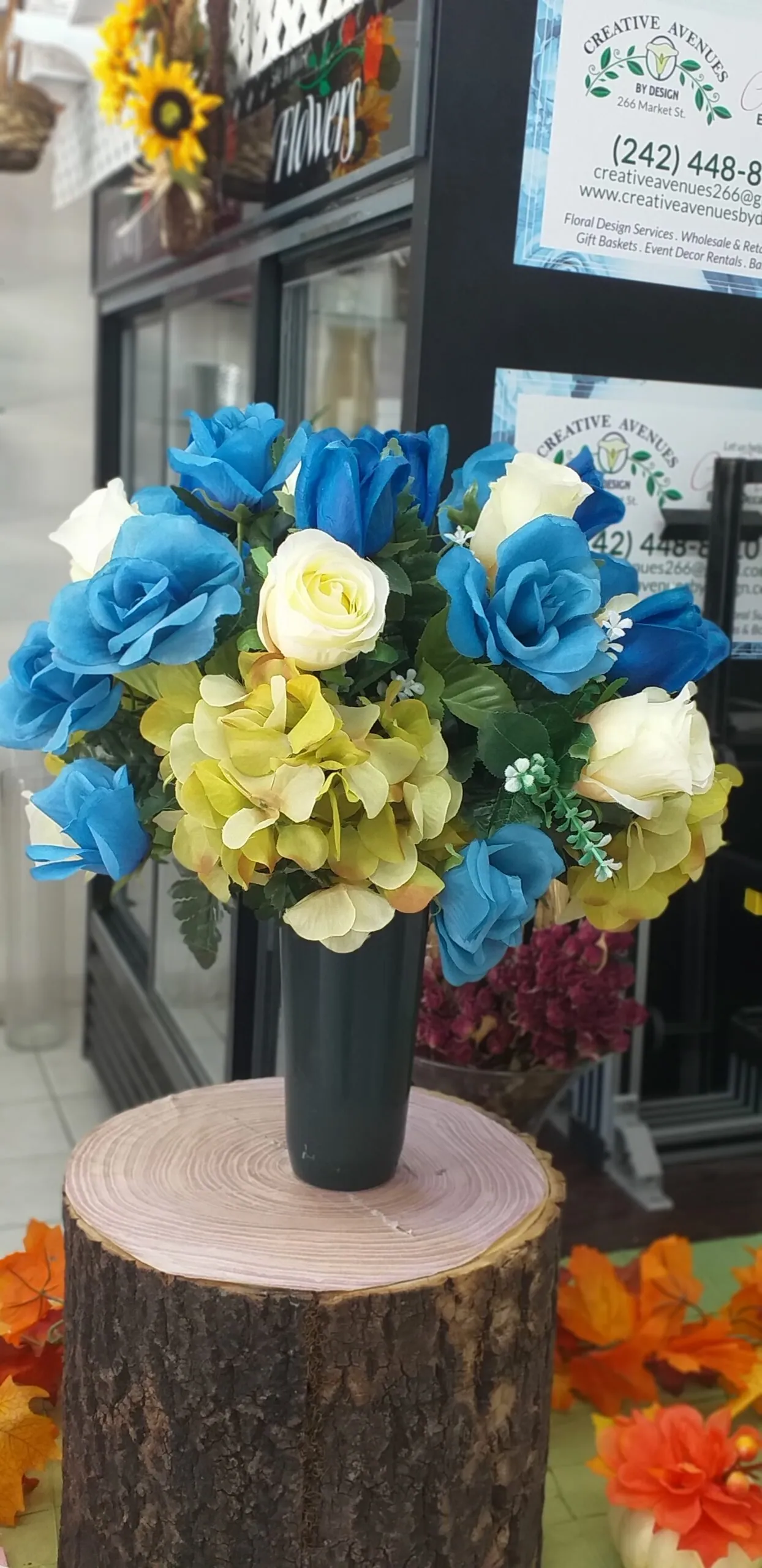 Blue and cream floral arrangement in a tall black vase, photographed at the Creative Avenues shop
