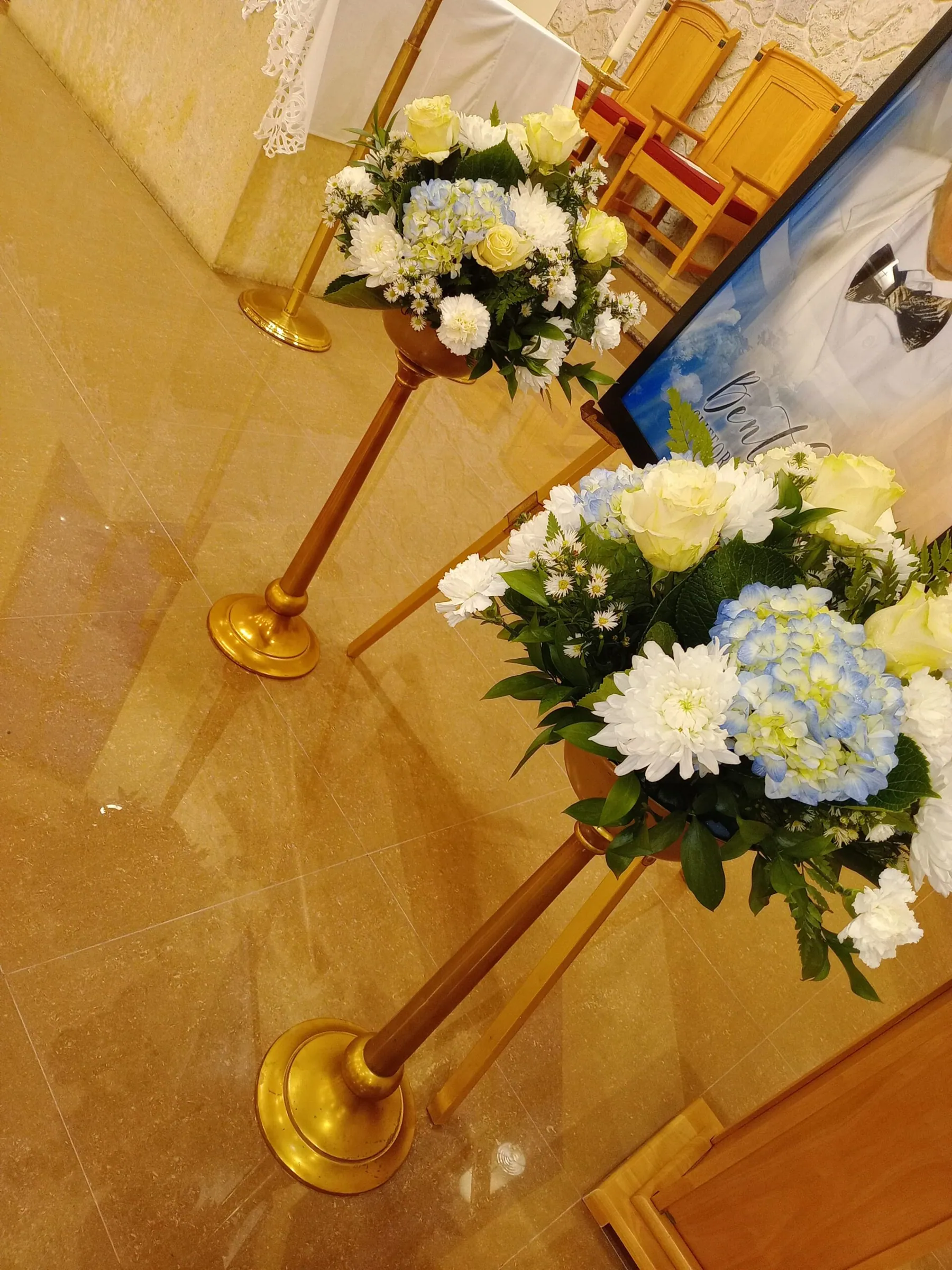 Pair of white and blue floral arrangements set along a church aisle by Creative Avenues