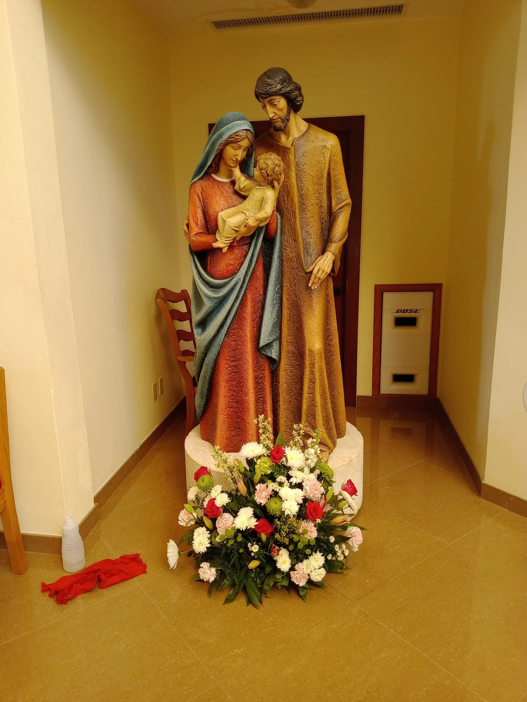 Floral arrangement placed at the base of a church statue by Creative Avenues in Nassau