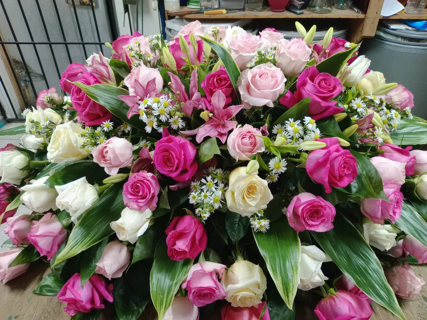 Casket spray of pink and white roses with foliage by Creative Avenues