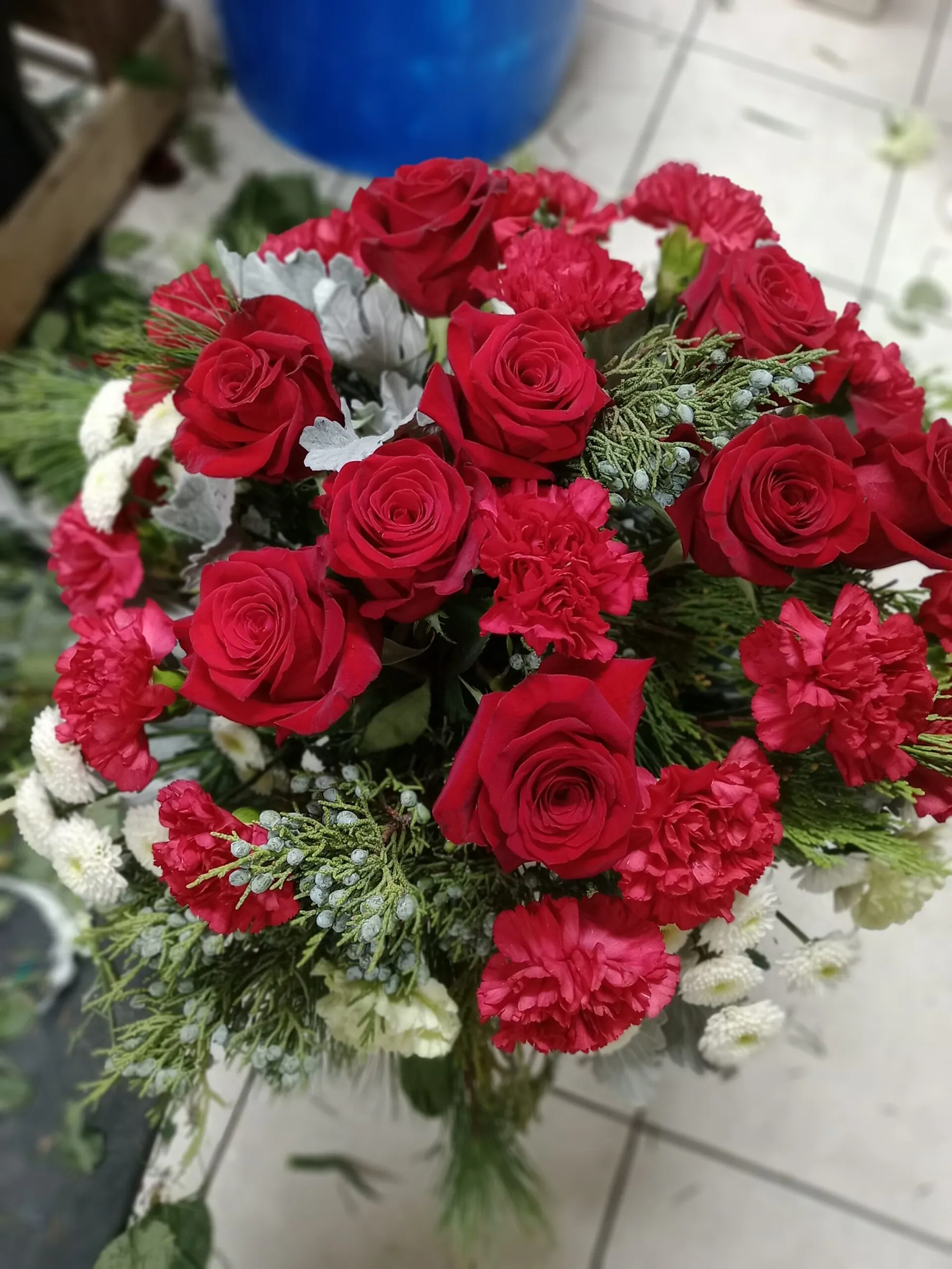 Hand-tied bouquet of red roses and carnations with white accents by Creative Avenues