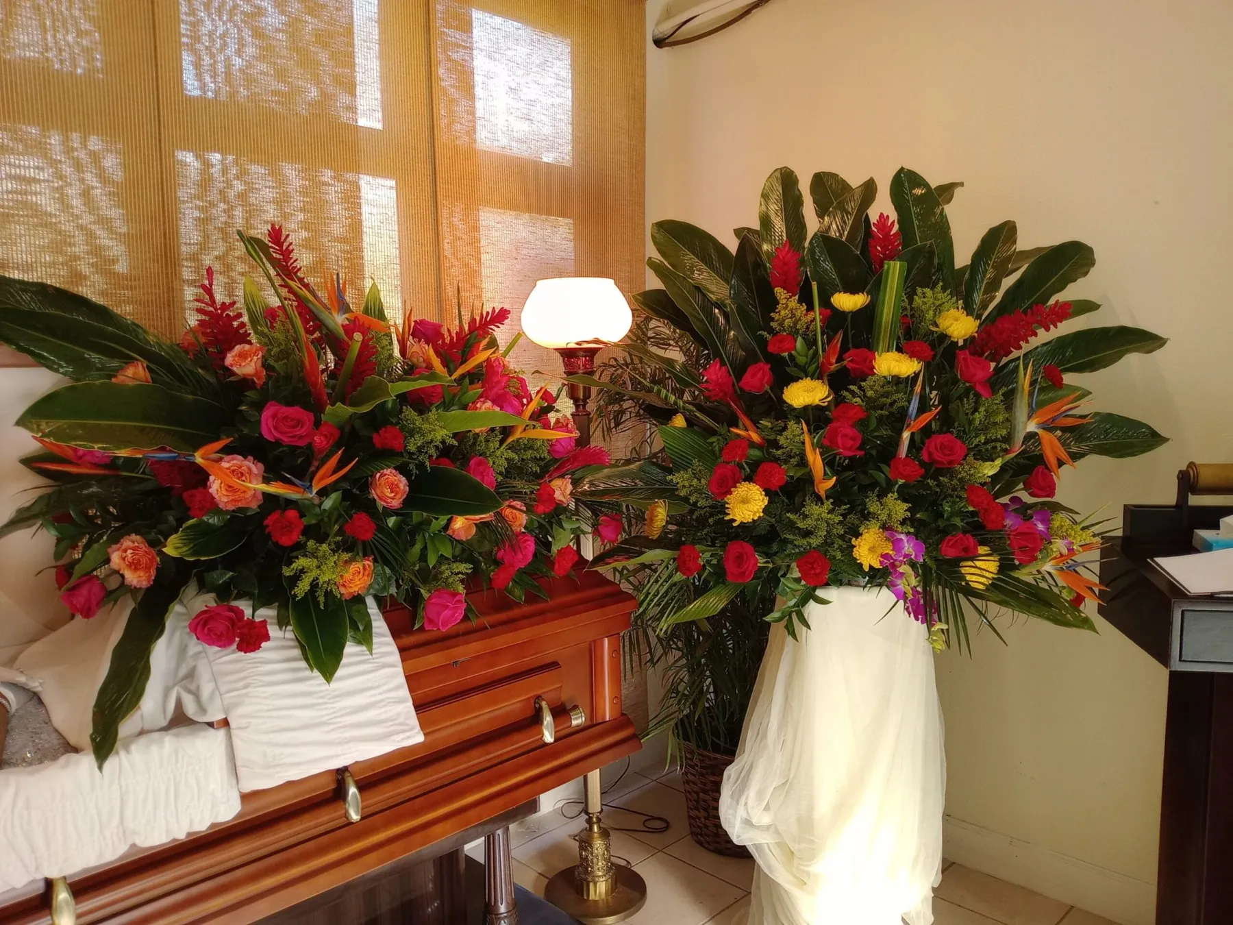 Tropical funeral spray with roses, gladiolus and foliage arranged by Creative Avenues