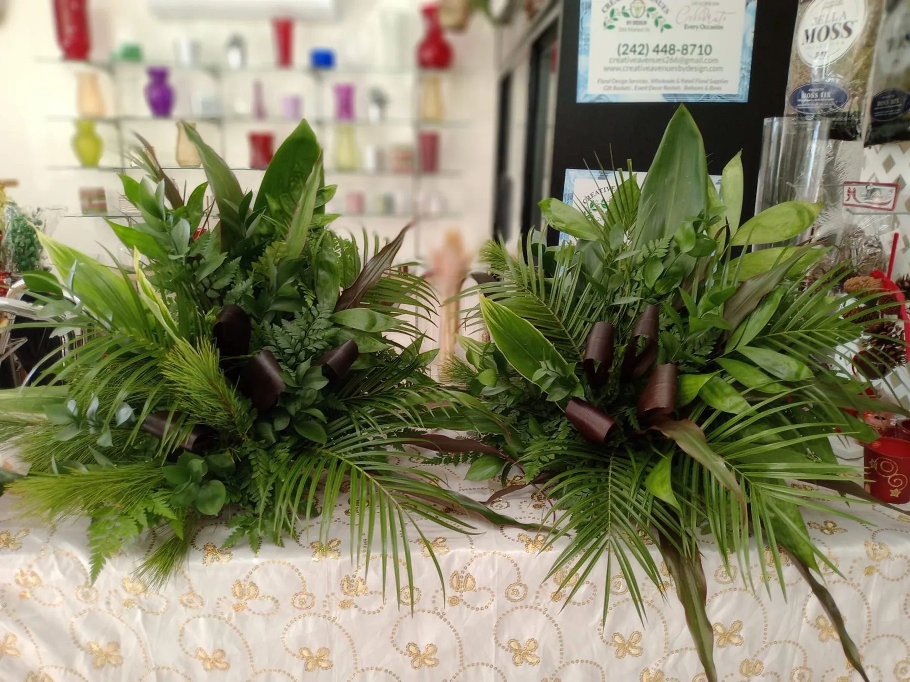 Row of tropical greenery table arrangements prepared for an event by Creative Avenues